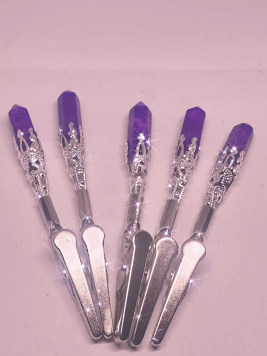 Set of five silver tools with purple handles on a light pink background