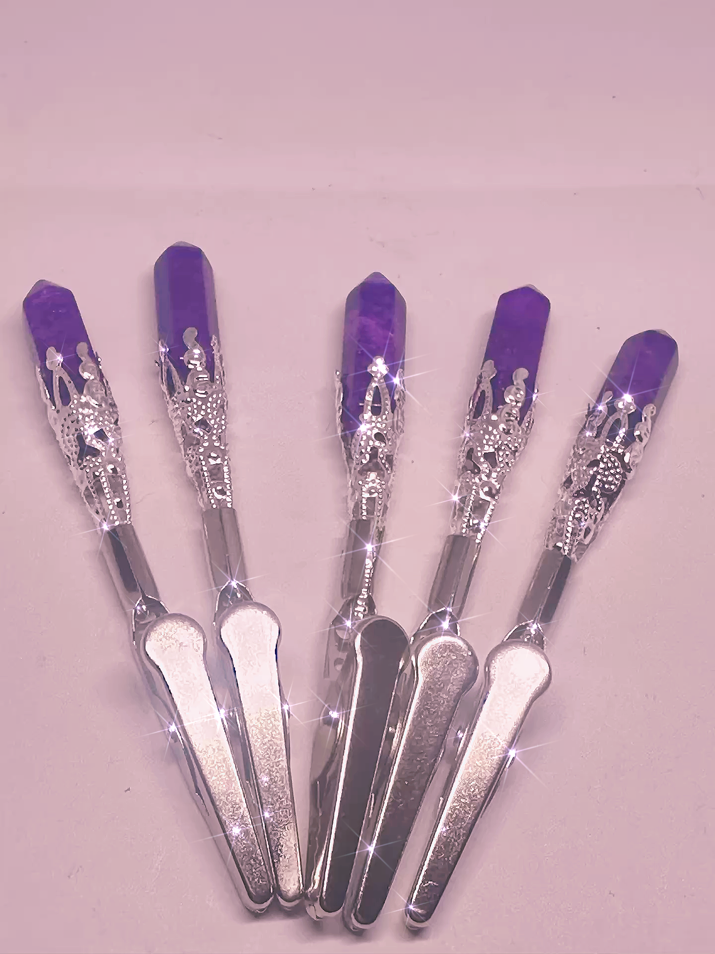 Set of five silver tools with purple handles on a light pink background