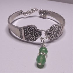 Silver bracelet with green beads on a white background