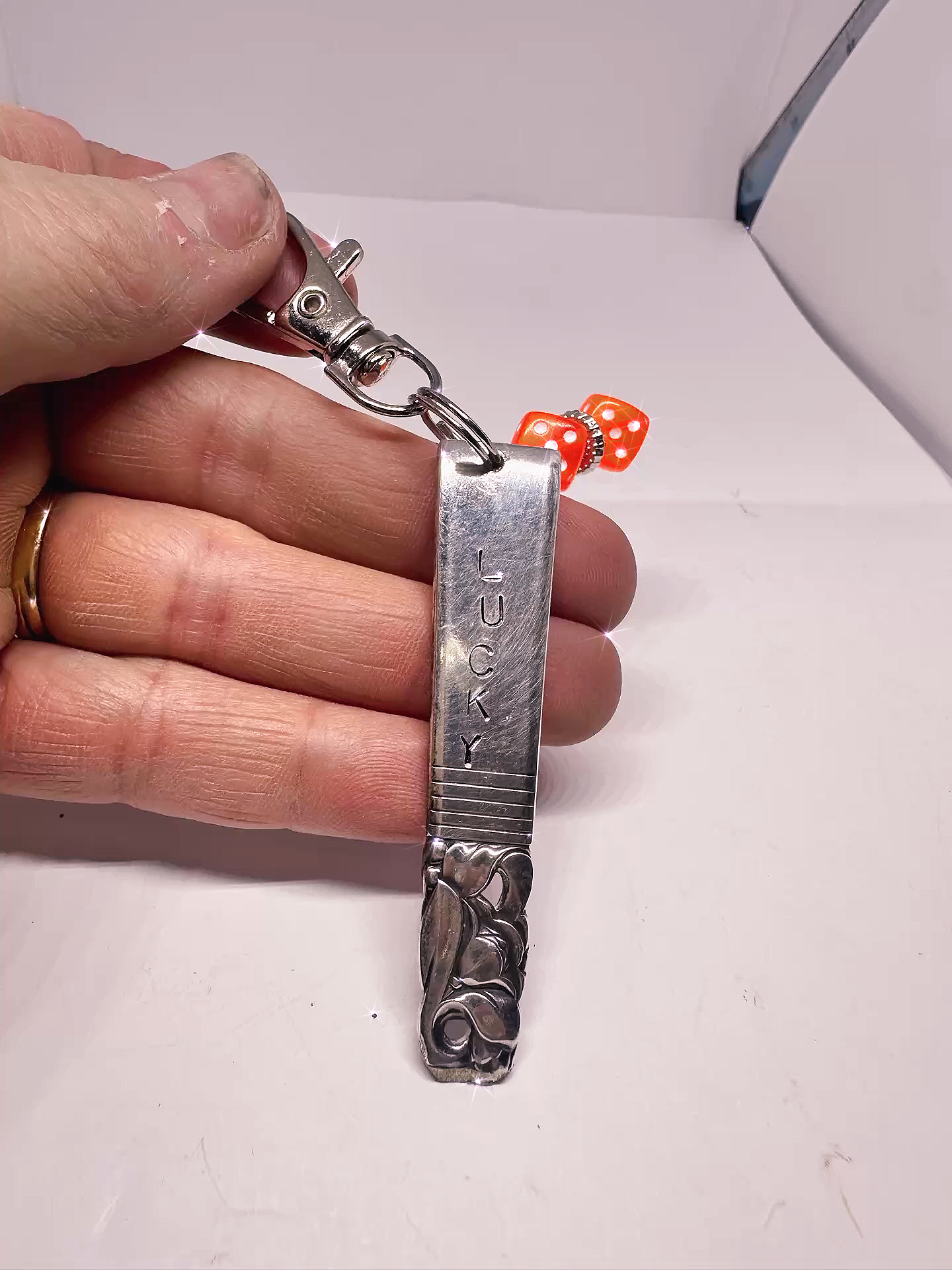 Close-up view of a Hand-Stamped Lucky Scratch Card Keychain – Upcycled Spoon with Dice Charm, displaying the 'LUCKY' stamp and red dice charm attached.