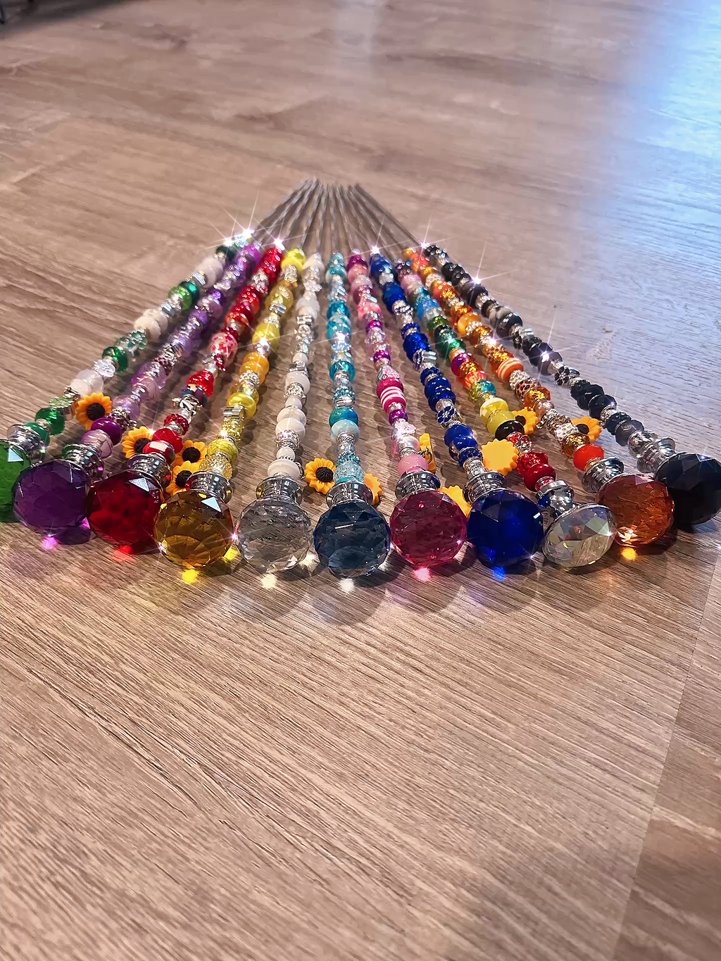 Colorful handmade garden fairy wands displayed in a row. Each wand features vibrant beads and sparkling crystals, making them a charming decorative plant stake. Perfect for plant lovers and a delightful gift idea.
