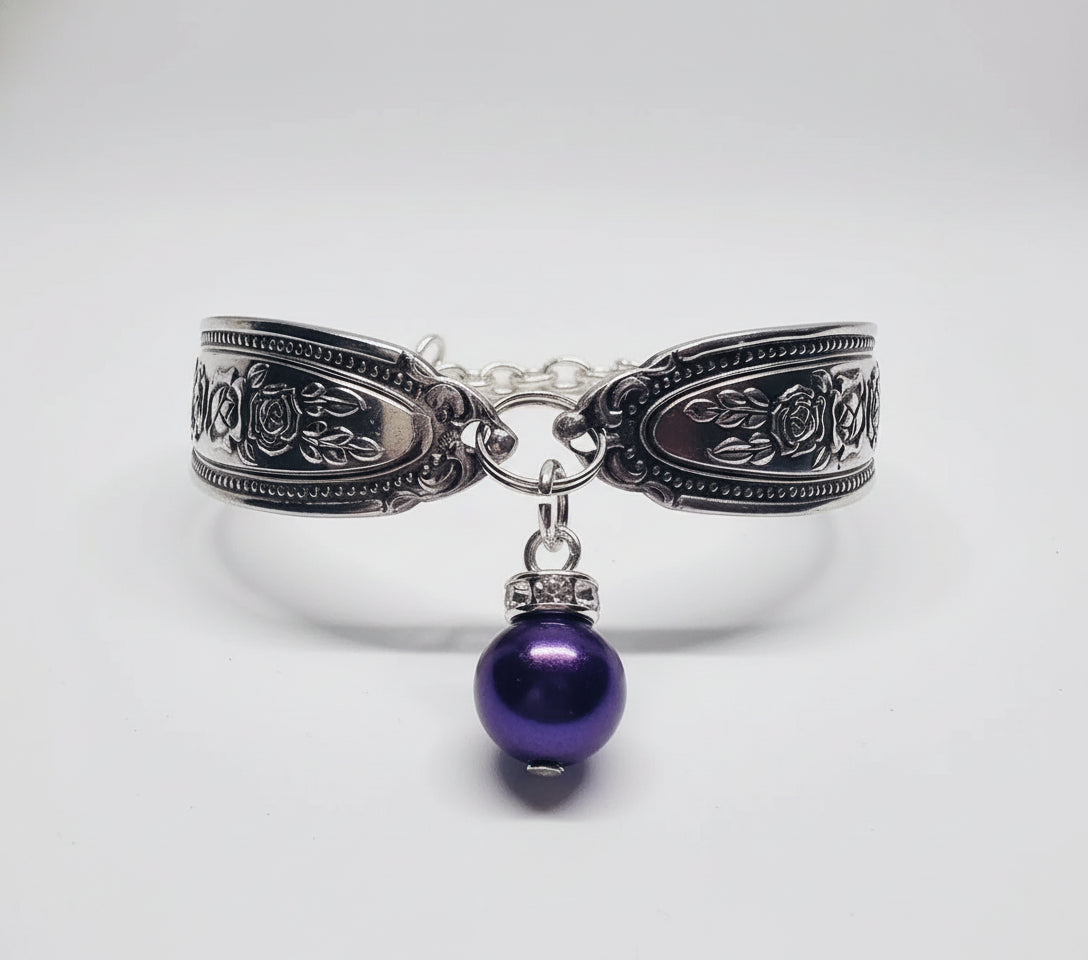 The Amethyst Spoon Bracelet with a deep purple amethyst cabochon hanging delicately, highlighting its unique blend of vintage and modern elegance.
