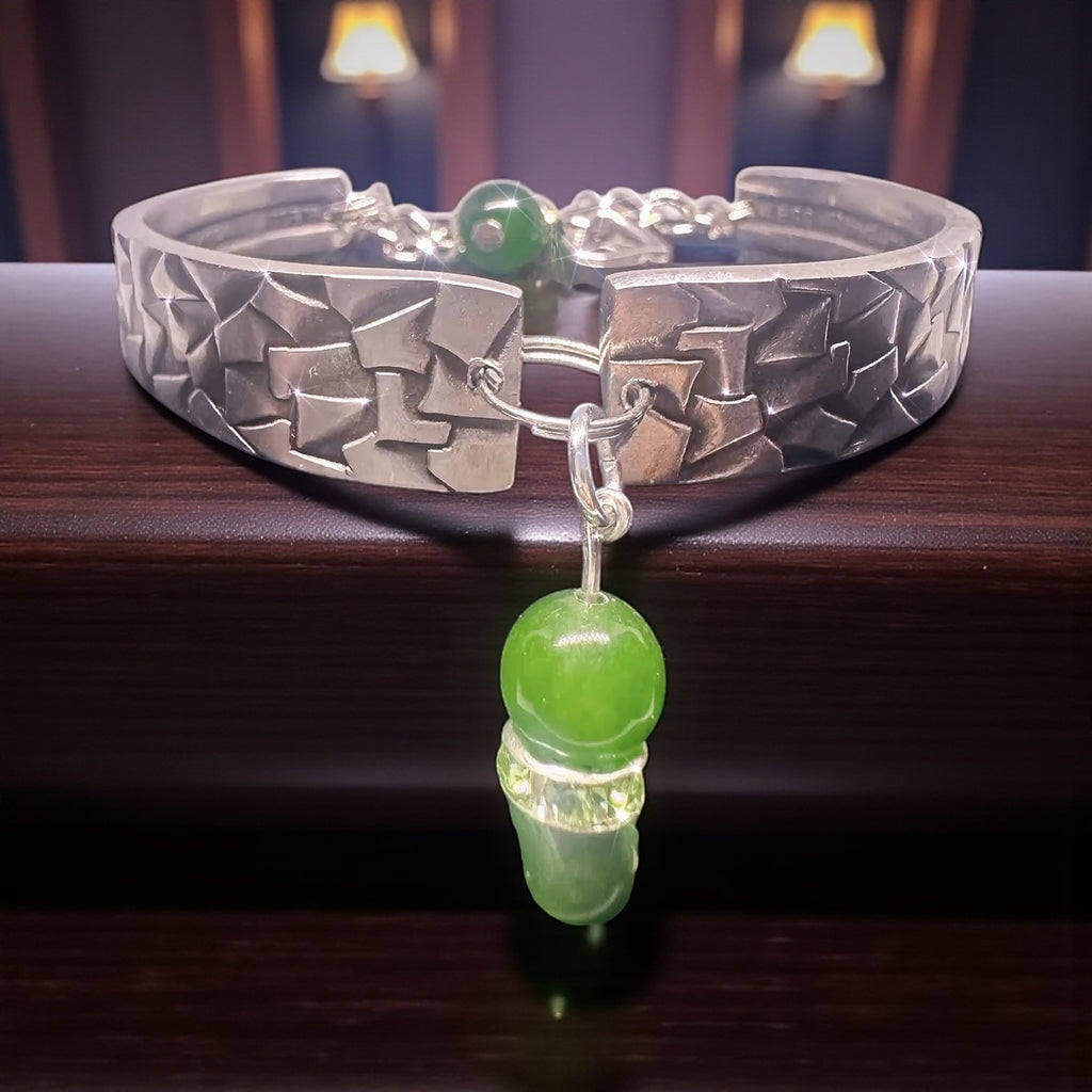 Silver bracelet with green beads on a wooden surface