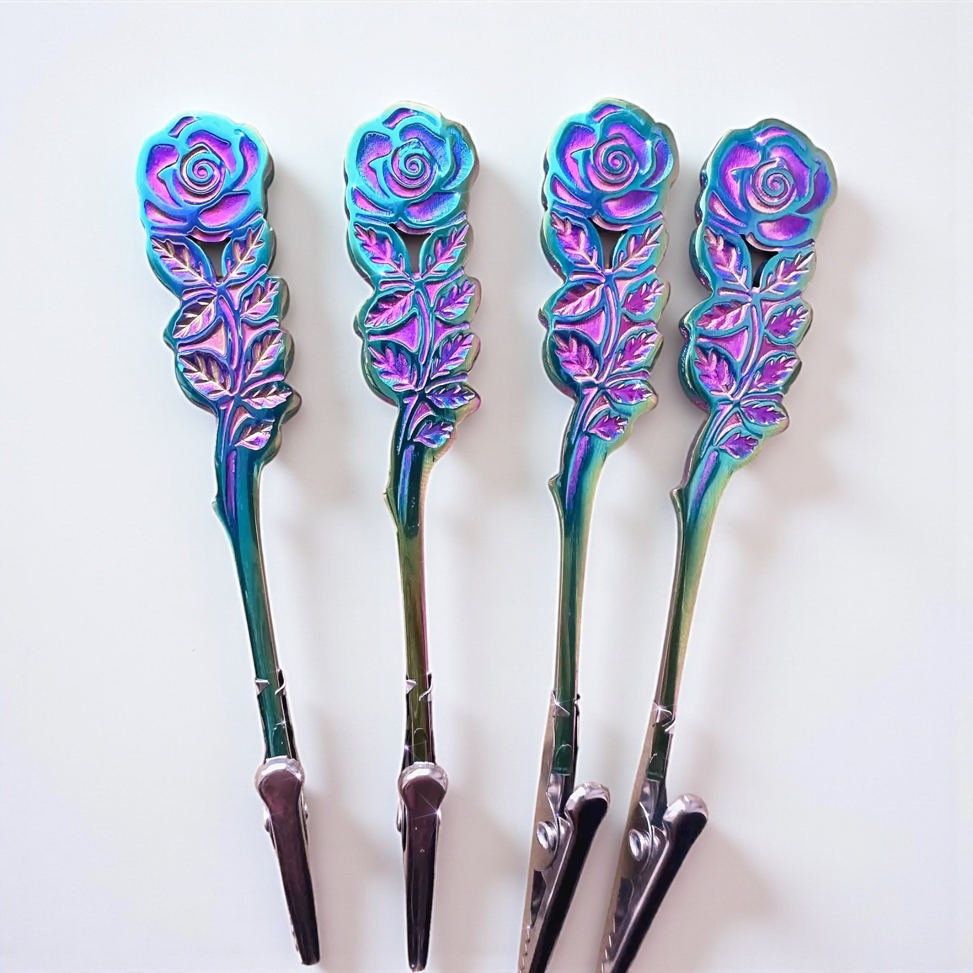 Four decorative spoons with rose designs on a white background