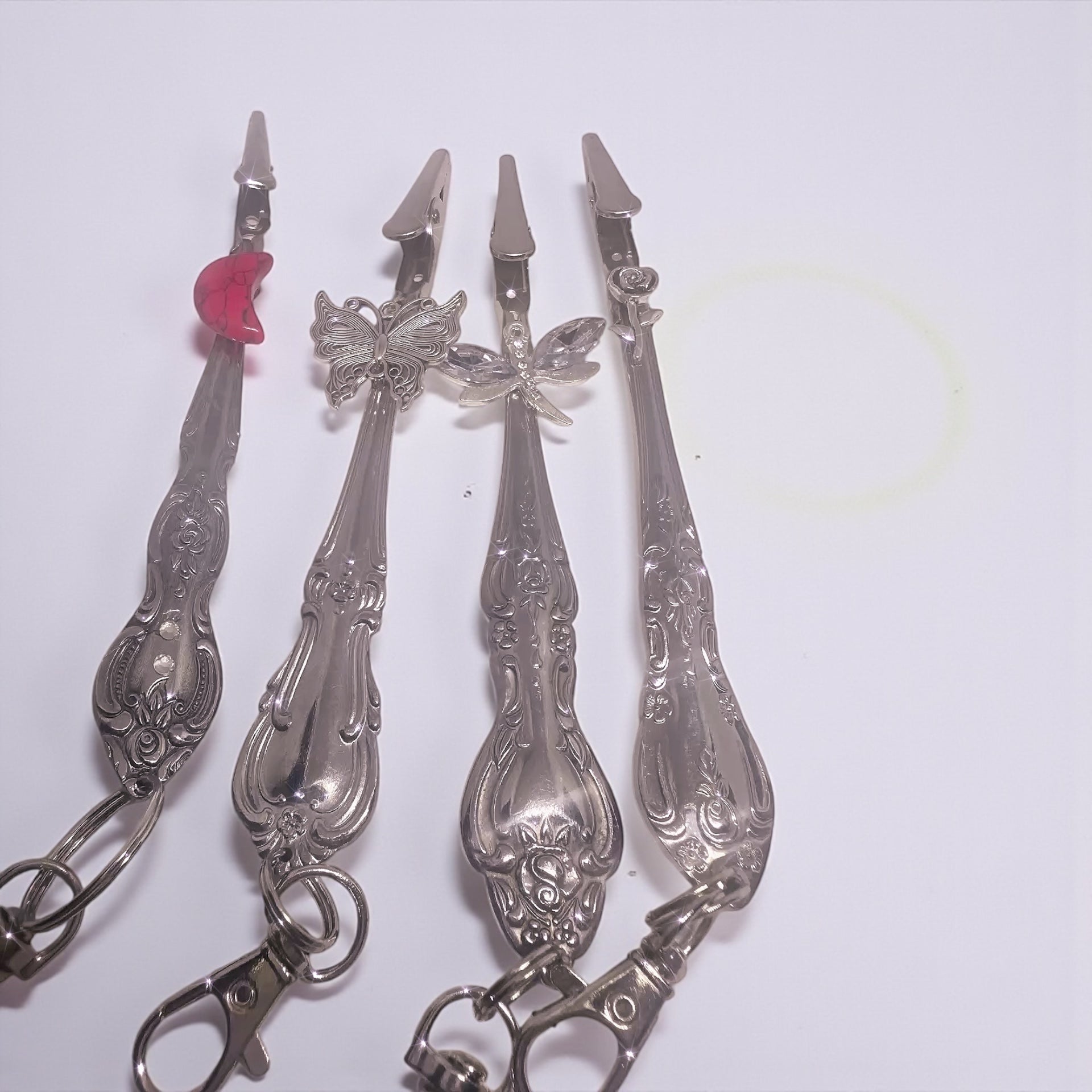 Set of decorative silver spoons with butterfly and floral designs on a white background