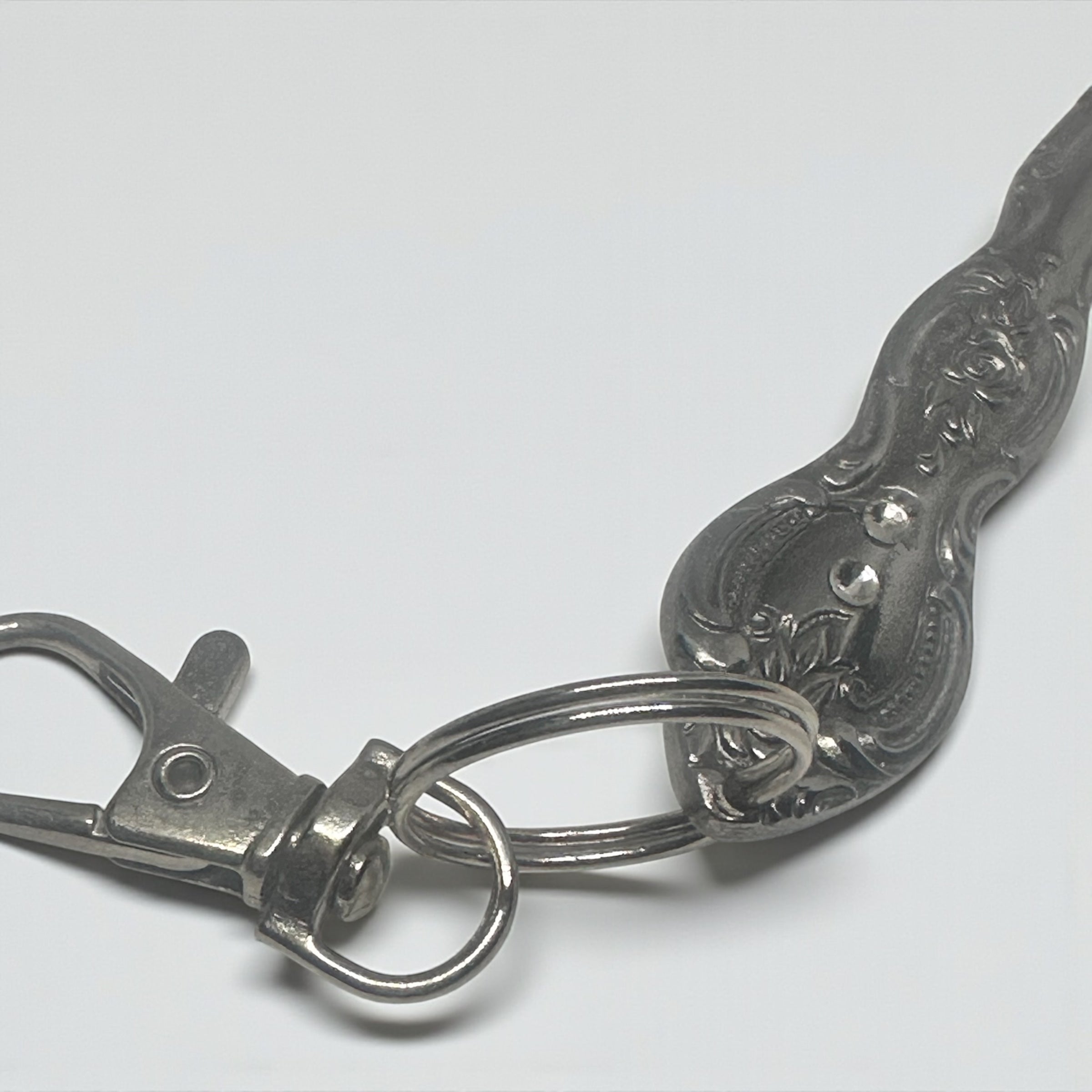 Silver keychain with intricate design on a white background