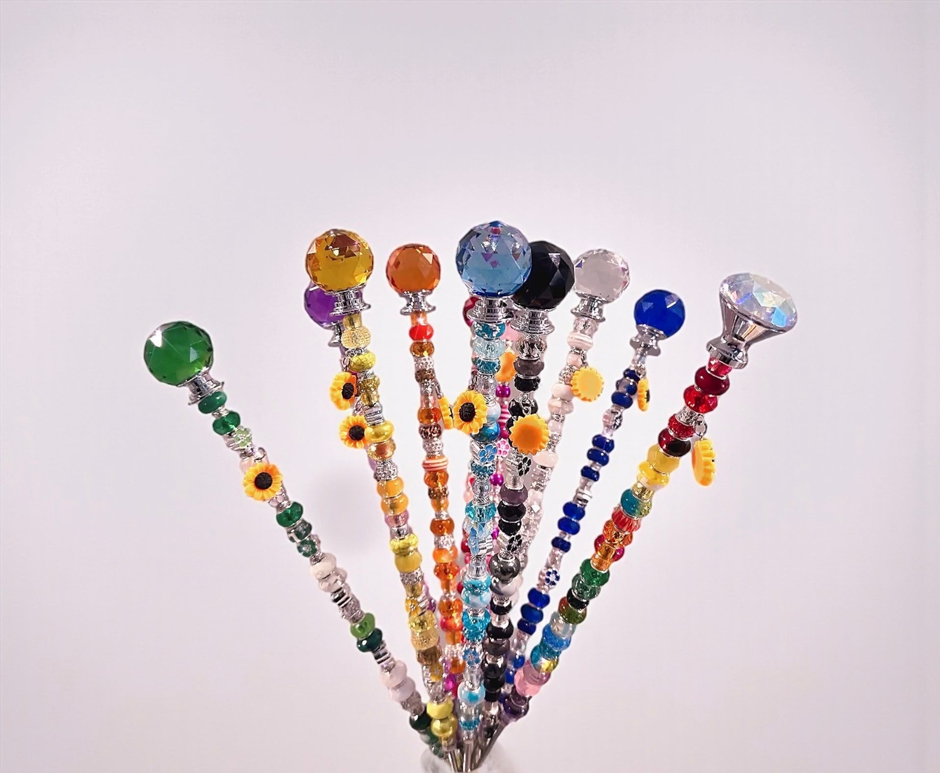 A close-up view of colorful handmade Garden Fairy Wands with various beads and a floral charm. Great for plant lovers seeking unique decorative plant stakes.