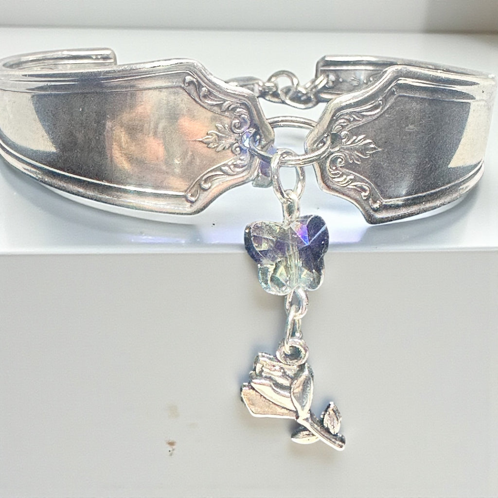 Silver spoon bracelet with a rose charm and crystal on a white background