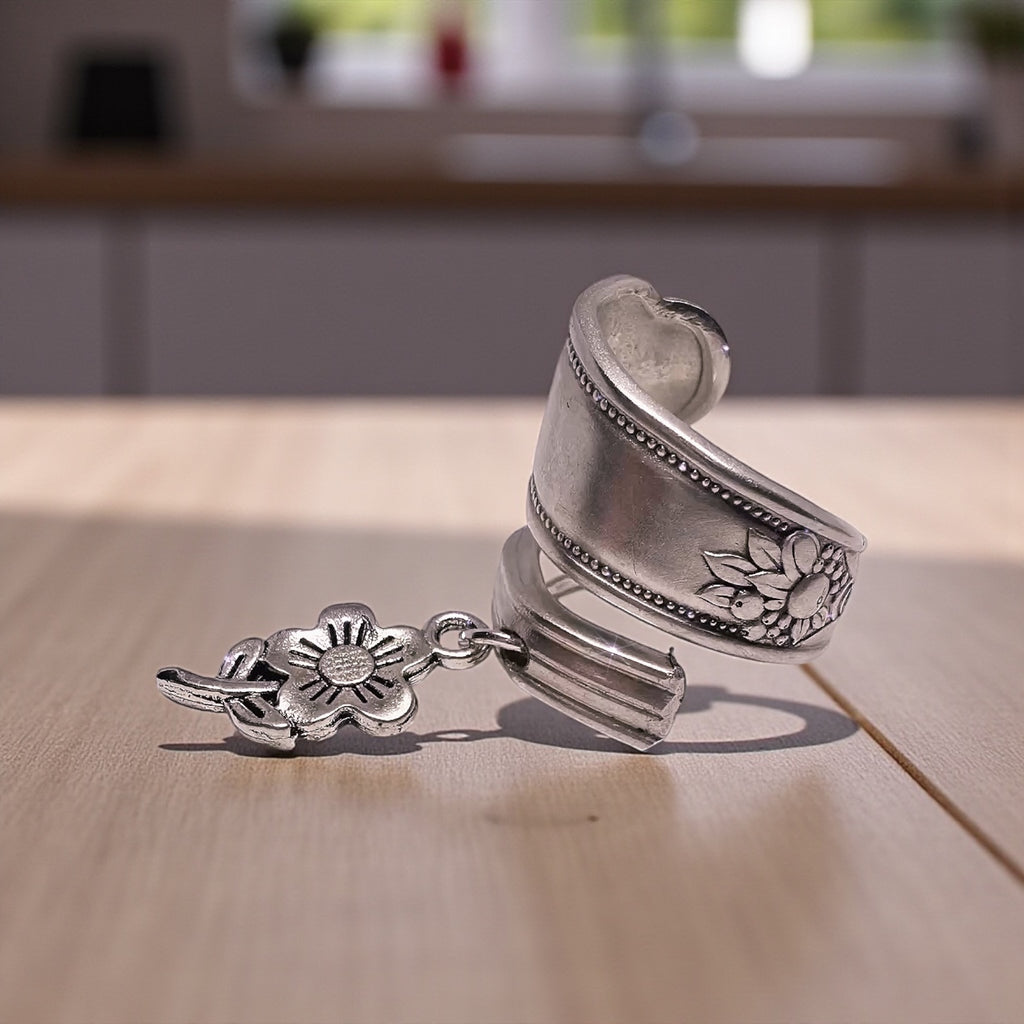 Silver spoon ring with floral charm on a wooden surface