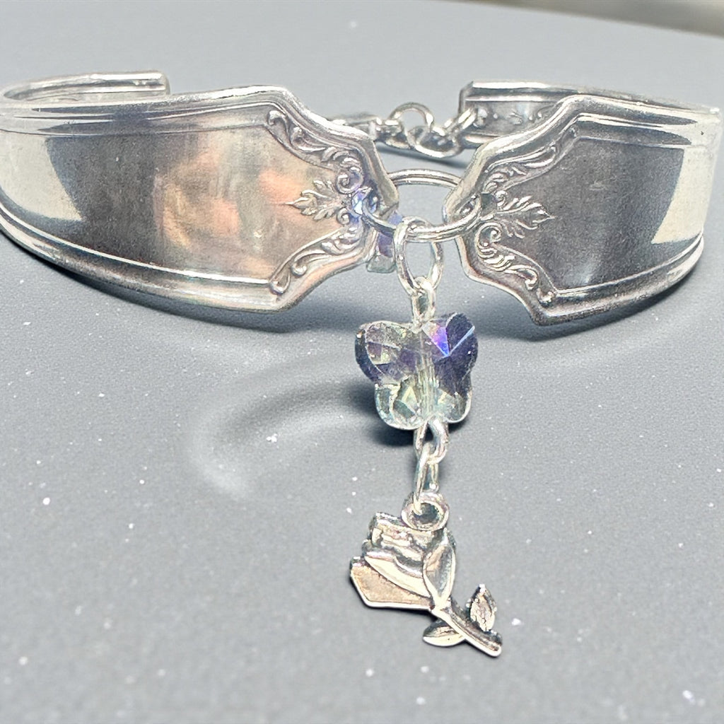 Silver bracelet with butterfly and rose charm on a gray background
