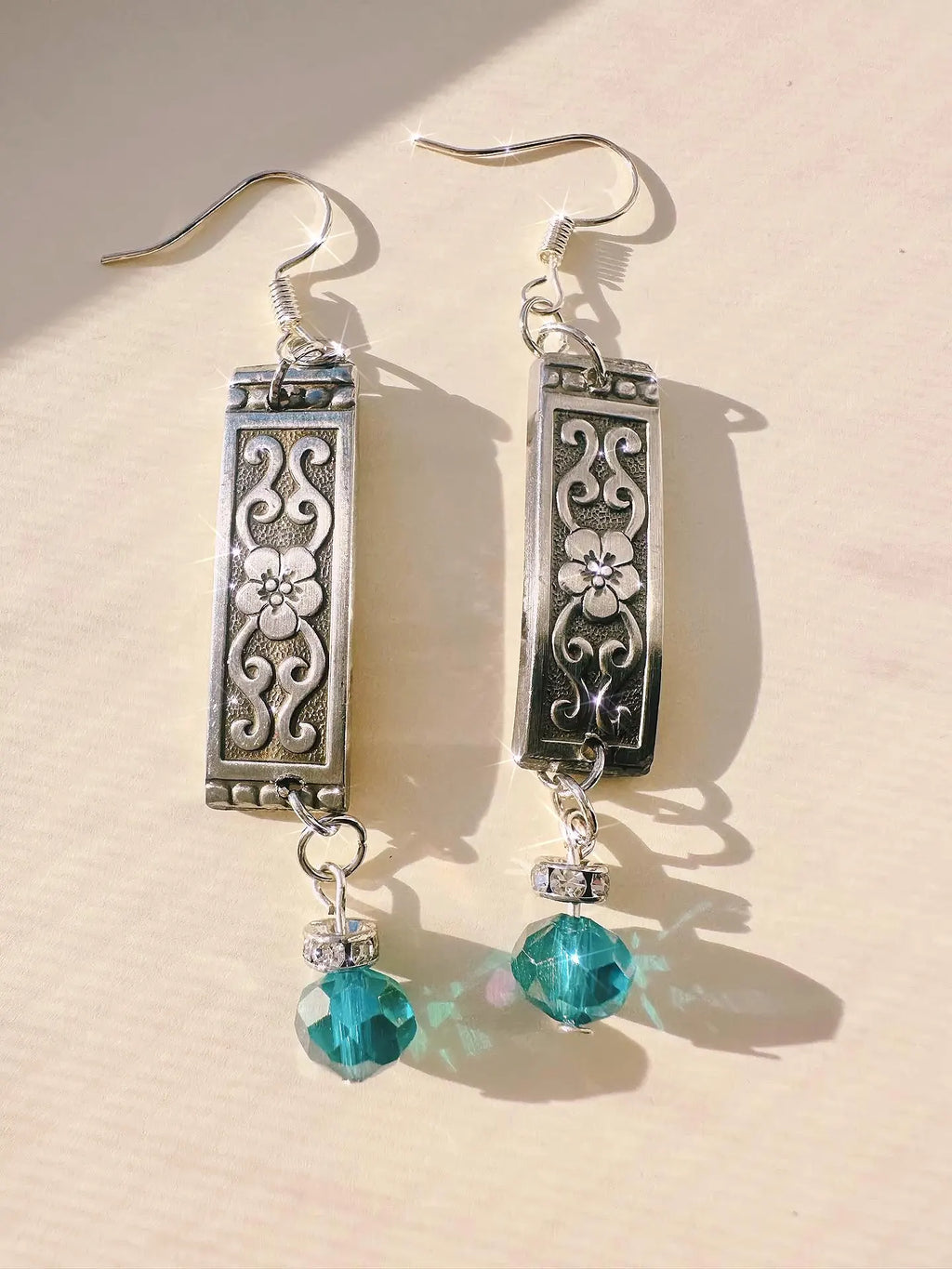 Custom Spoon Jewelry - Handcrafted earrings featuring intricate silver designs and turquoise crystal accents.