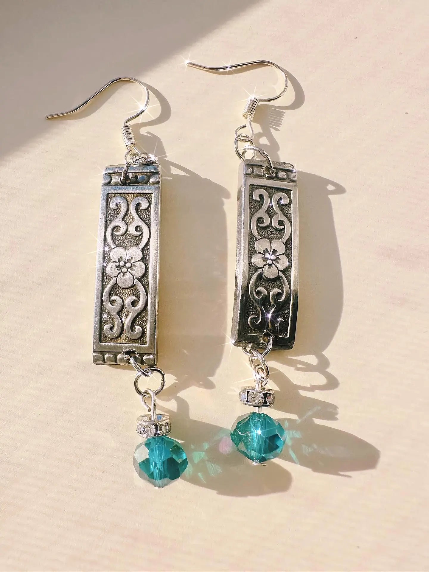 Custom Spoon Jewelry - Handcrafted earrings featuring intricate silver designs and turquoise crystal accents.