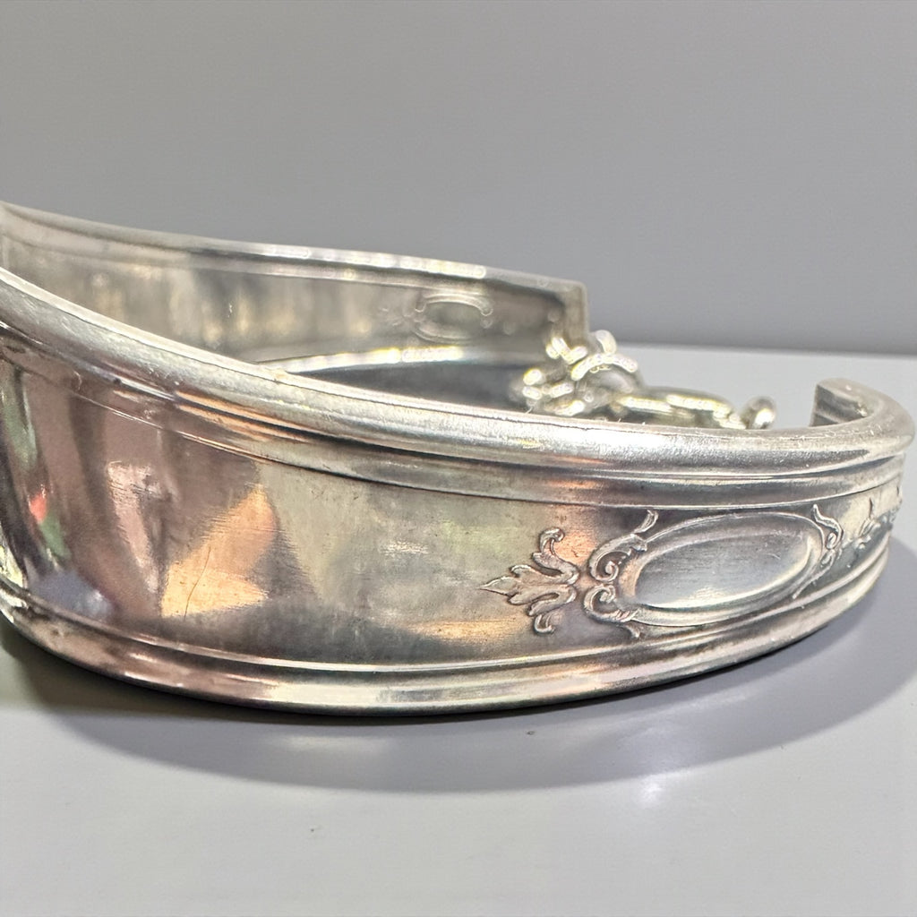 Silver bracelet with intricate designs on a light gray background