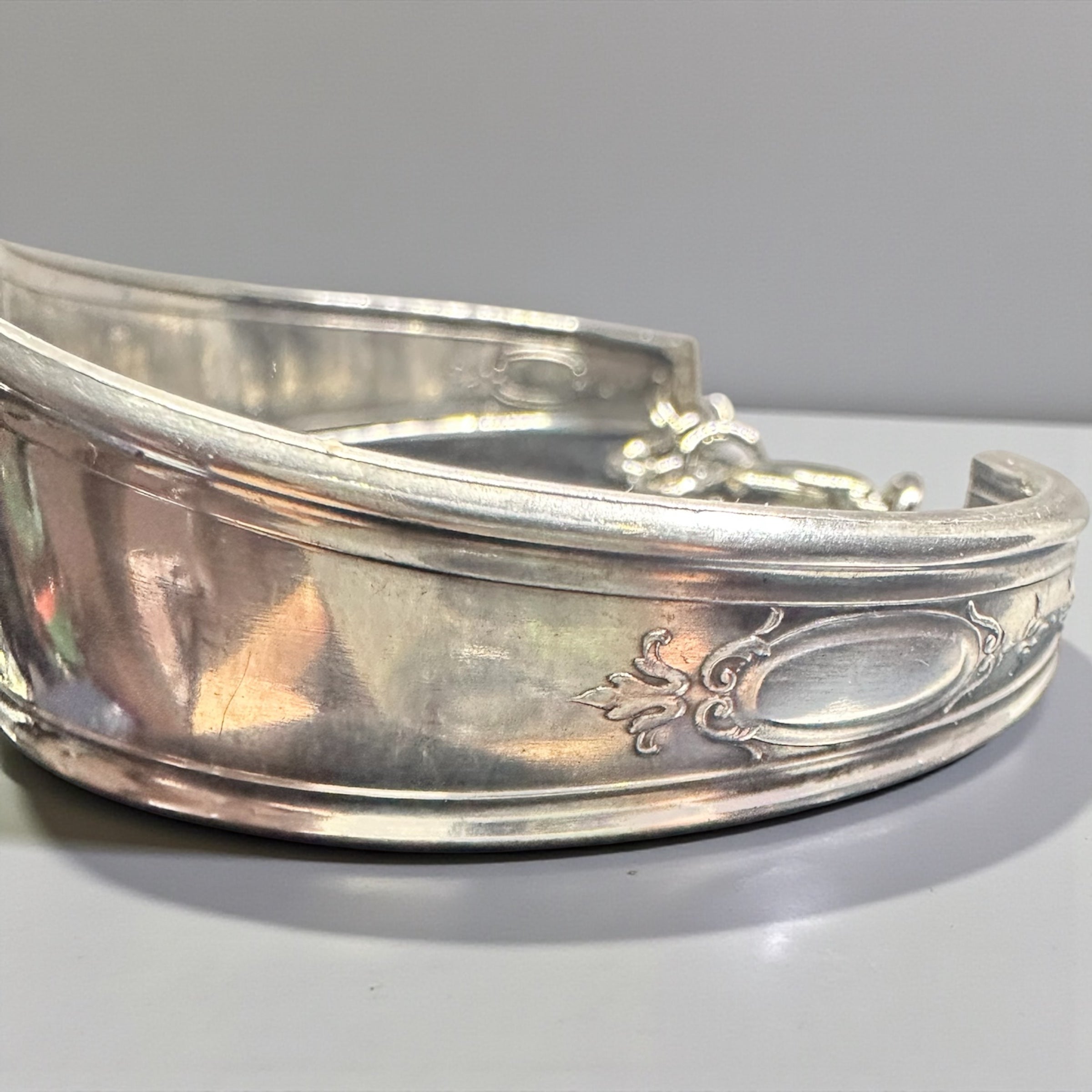 Silver bracelet with intricate designs on a light gray background