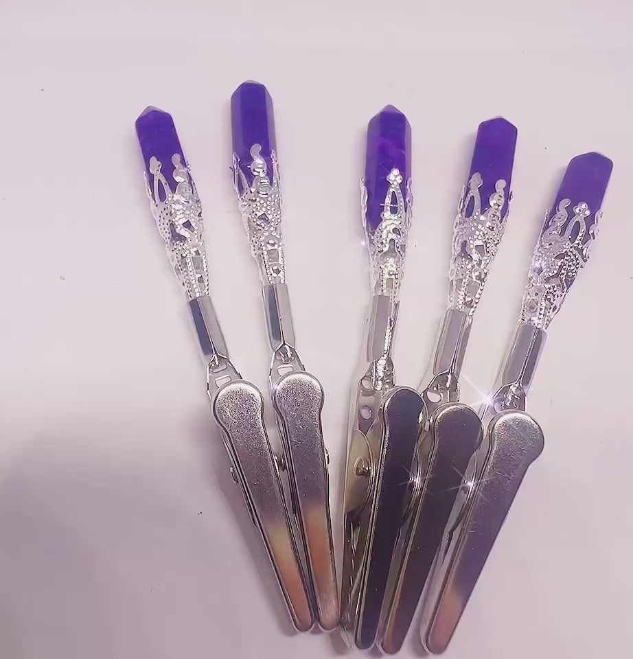 Silver batm card clip with interlocking texture and green beaded charm, displayed on dark wood with warm lighting.