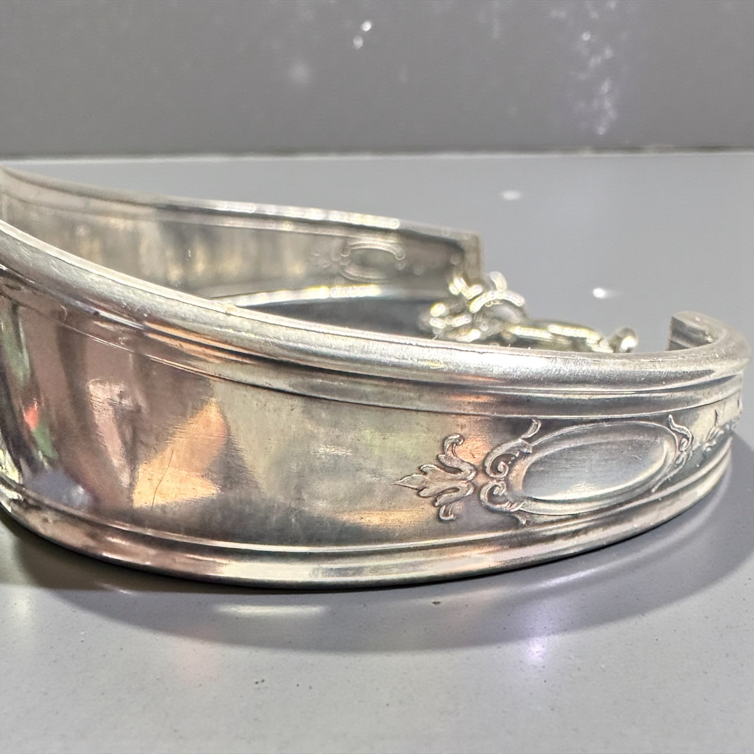 Silver bracelet with intricate designs on a gray background