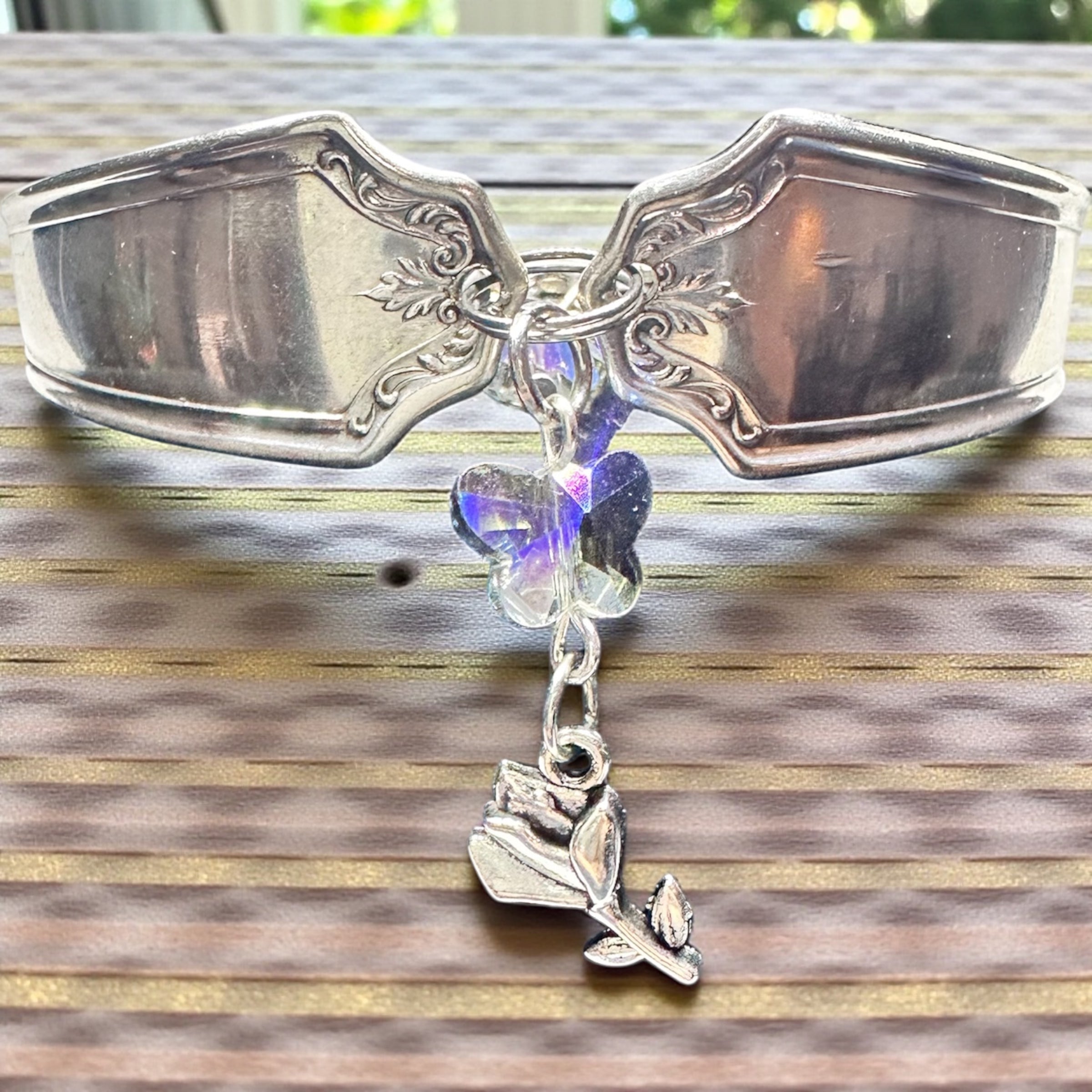Silver spoon bracelet with butterfly charm on a wooden surface
