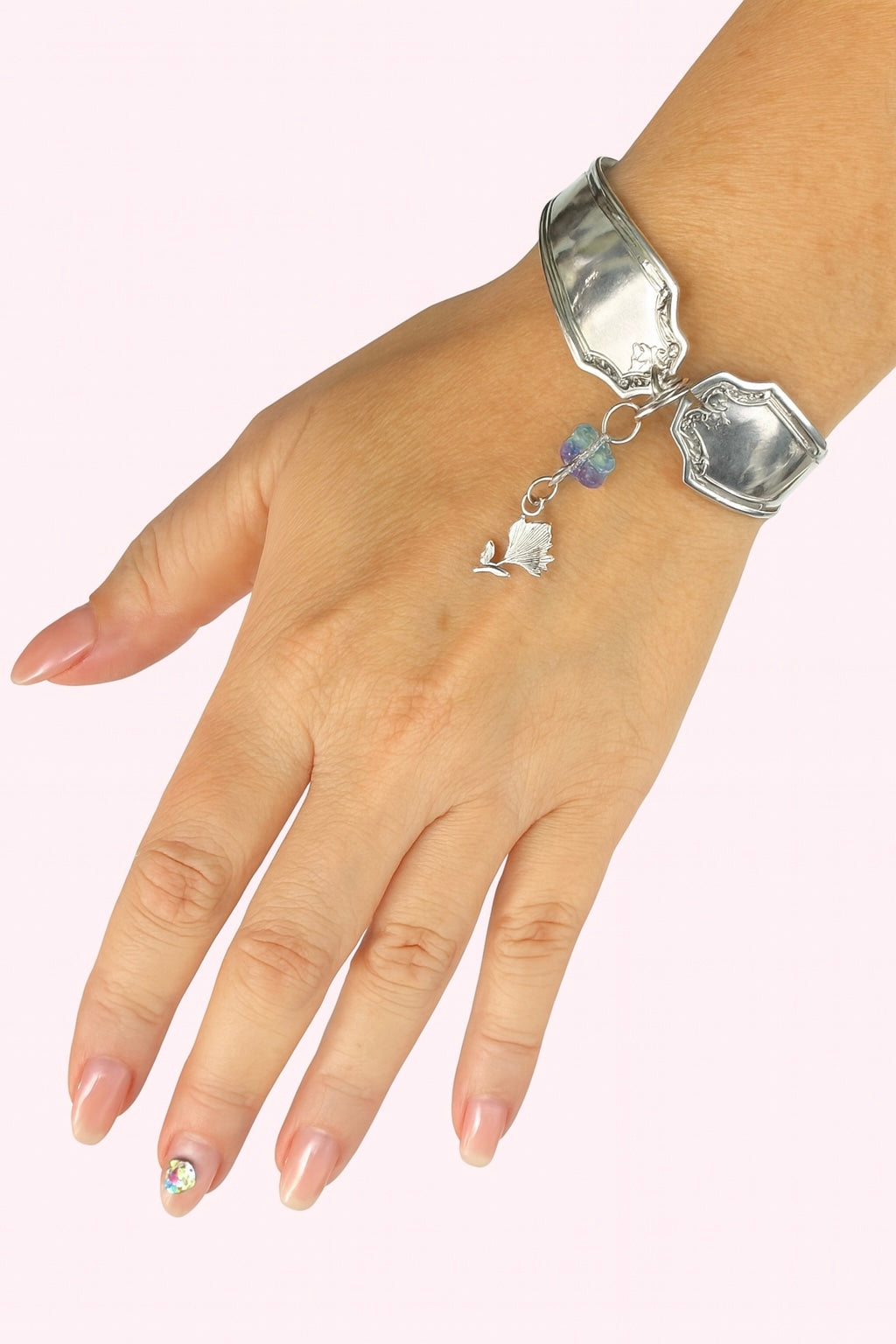 Silver bracelet with charms on a wrist against a white background