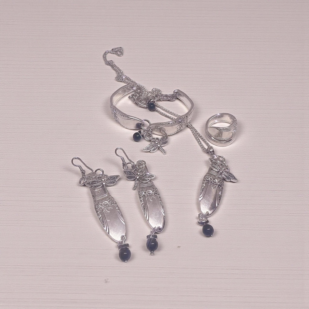 Silver spoon  jewelry set with rings and pendants on a light gray background
