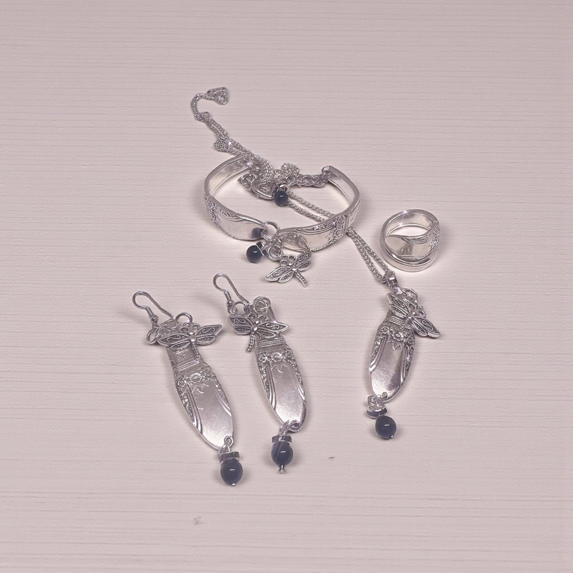 Silver spoon  jewelry set with rings and pendants on a light gray background